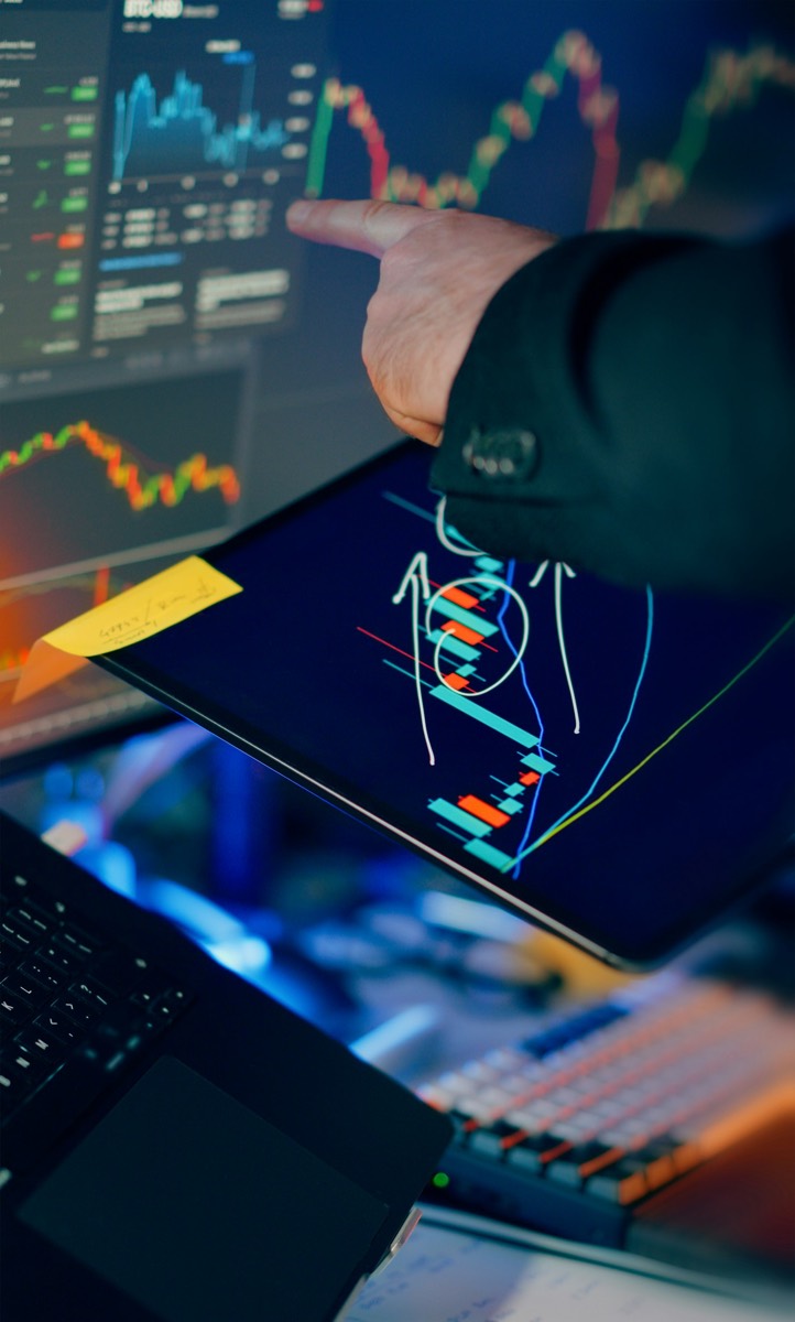 Analyst reviewing stock market charts on multiple screens
